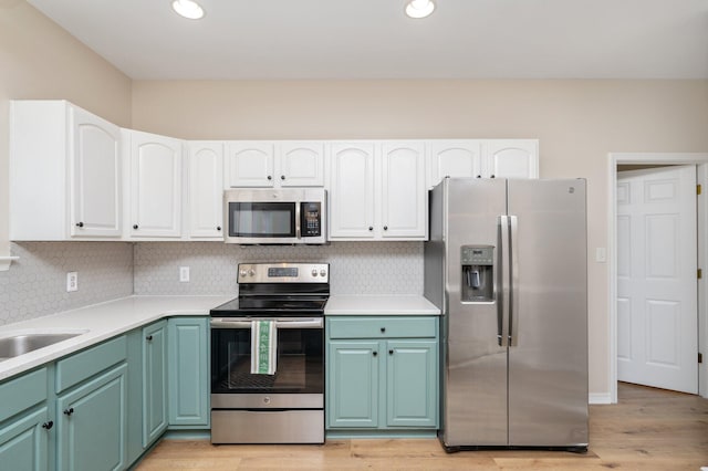 kitchen featuring white cabinets, appliances with stainless steel finishes, backsplash, and light hardwood / wood-style flooring