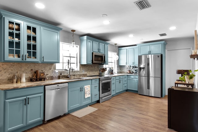 kitchen featuring blue cabinets, decorative light fixtures, and appliances with stainless steel finishes