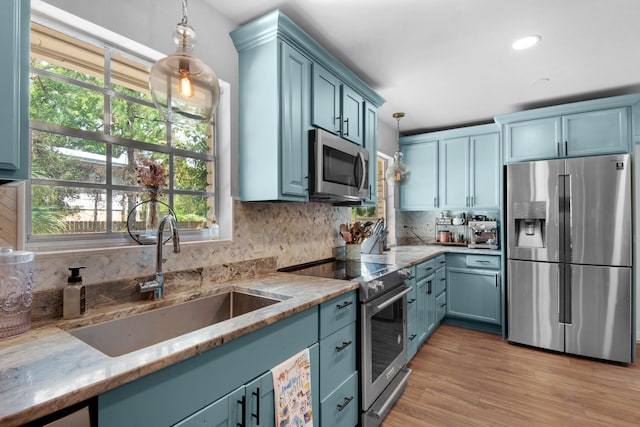 kitchen with appliances with stainless steel finishes, pendant lighting, sink, and plenty of natural light