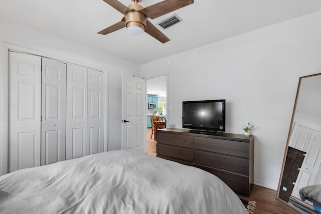 bedroom with dark wood-type flooring, ceiling fan, and a closet