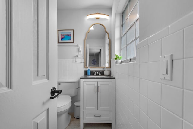 bathroom featuring tile patterned floors, tile walls, toilet, and vanity