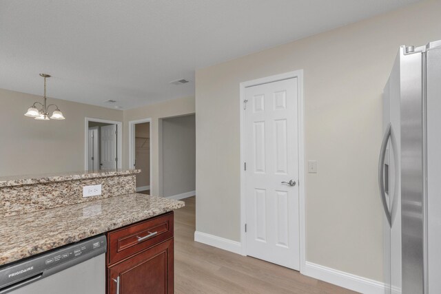 kitchen with pendant lighting, a notable chandelier, light hardwood / wood-style flooring, stainless steel appliances, and light stone countertops