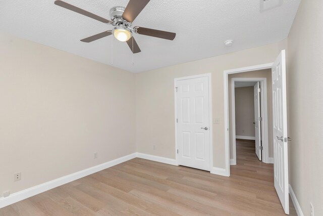 empty room with light wood-type flooring, a textured ceiling, and ceiling fan