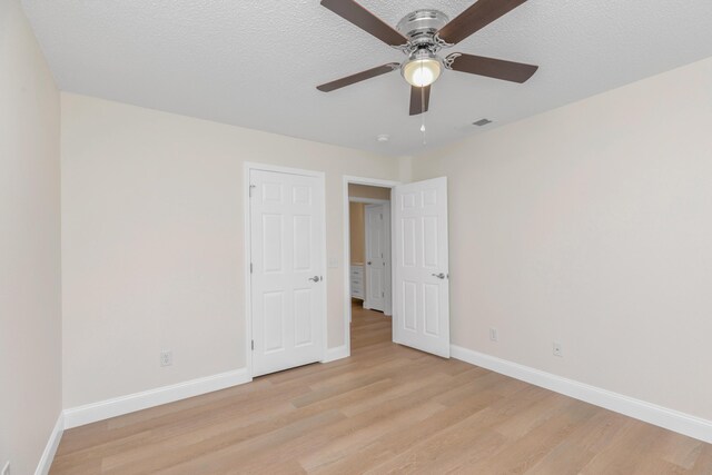 unfurnished room with a textured ceiling, light hardwood / wood-style flooring, and ceiling fan