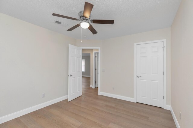 unfurnished bedroom with ceiling fan, a textured ceiling, and light hardwood / wood-style flooring