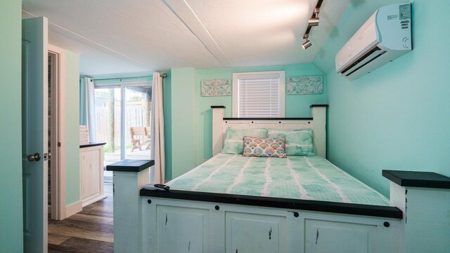 bedroom featuring dark wood-type flooring, track lighting, and a wall mounted air conditioner