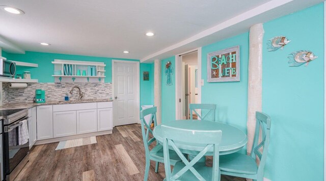 kitchen featuring tasteful backsplash, light hardwood / wood-style flooring, electric range, light stone countertops, and white cabinets