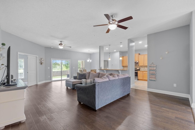 living room with dark hardwood / wood-style flooring, ceiling fan, and a textured ceiling