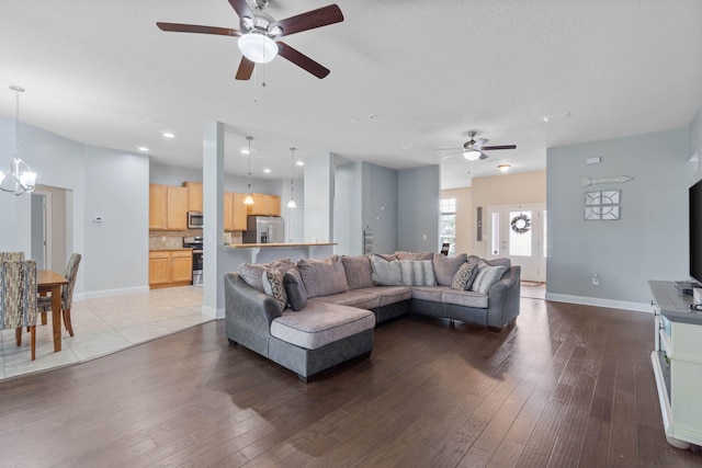 living room with ceiling fan with notable chandelier and hardwood / wood-style flooring