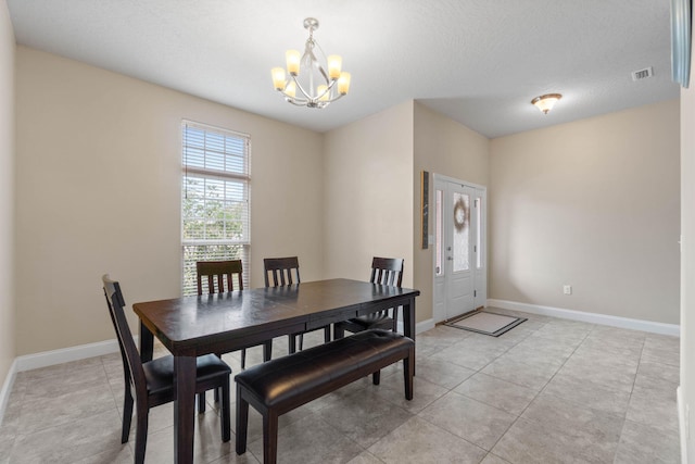 tiled dining space featuring a textured ceiling and an inviting chandelier