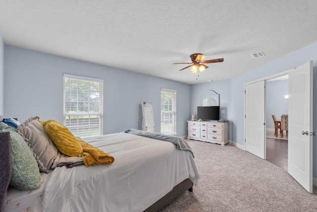 bedroom with ceiling fan, carpet, and a textured ceiling