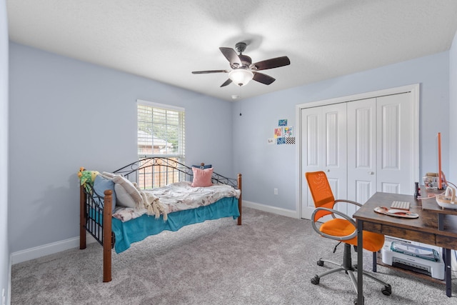 carpeted bedroom with a textured ceiling, ceiling fan, and a closet