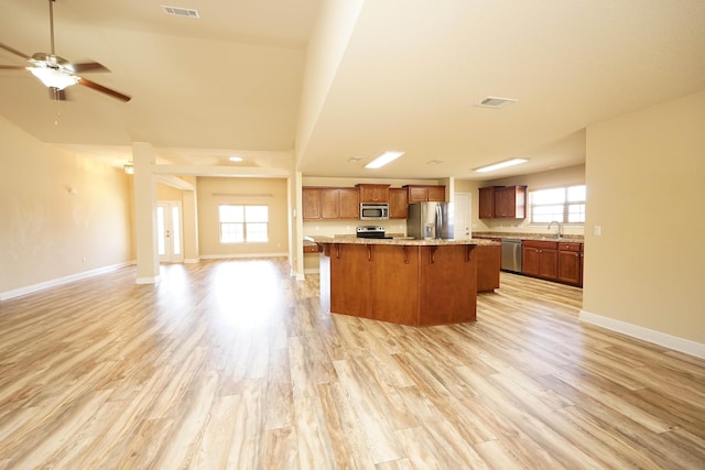 kitchen with sink, light hardwood / wood-style floors, a breakfast bar area, a kitchen island, and appliances with stainless steel finishes