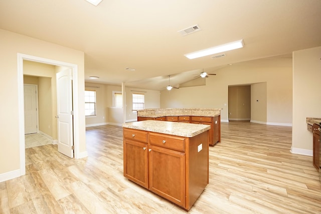 kitchen featuring ceiling fan, a center island, lofted ceiling, and light wood-type flooring