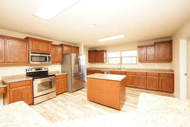 kitchen with sink, a kitchen island, stainless steel appliances, and light hardwood / wood-style floors