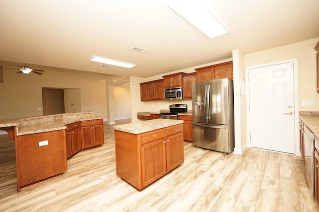 kitchen with ceiling fan, light stone countertops, a breakfast bar, a kitchen island, and appliances with stainless steel finishes