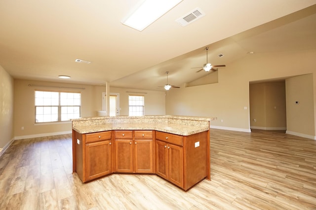 kitchen featuring ceiling fan, a center island, lofted ceiling, and light hardwood / wood-style flooring