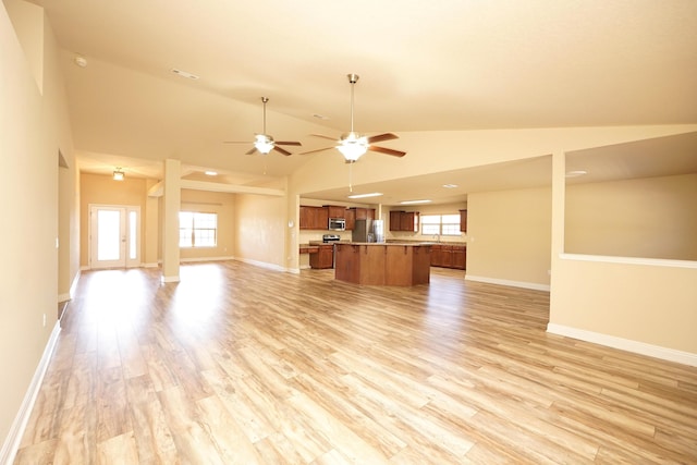 unfurnished living room featuring ceiling fan, plenty of natural light, light hardwood / wood-style floors, and vaulted ceiling