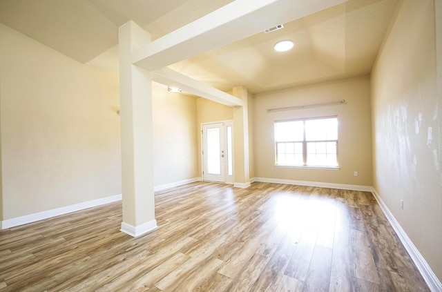 spare room featuring a raised ceiling and light hardwood / wood-style flooring