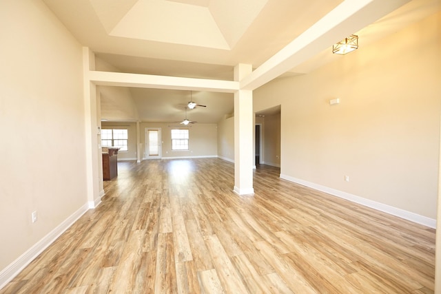 unfurnished living room with light wood-type flooring, a raised ceiling, and ceiling fan