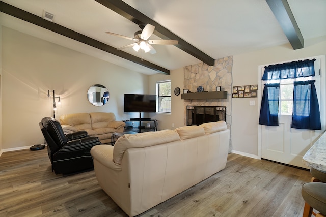 living room with a fireplace, ceiling fan, hardwood / wood-style floors, and vaulted ceiling with beams