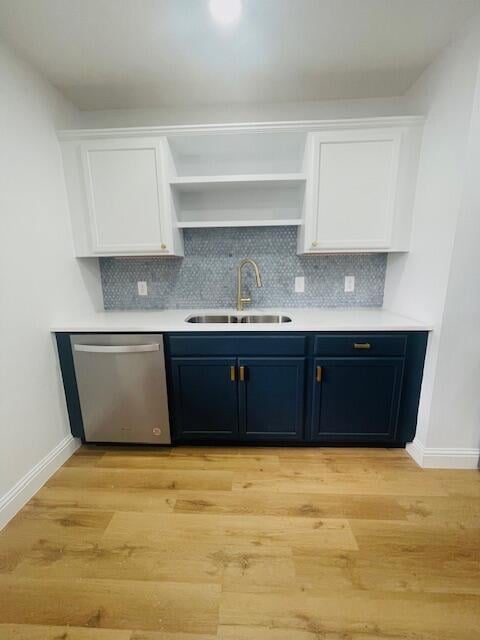 kitchen featuring stainless steel dishwasher, light wood-type flooring, sink, and tasteful backsplash