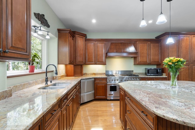 kitchen with light stone counters, sink, hanging light fixtures, custom exhaust hood, and stainless steel appliances