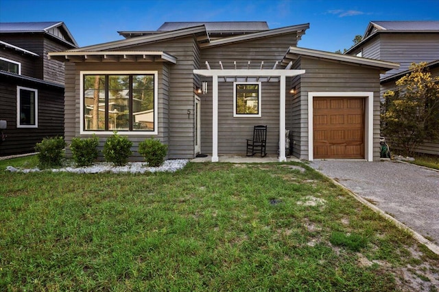 view of front of property with a garage, a front yard, and a pergola