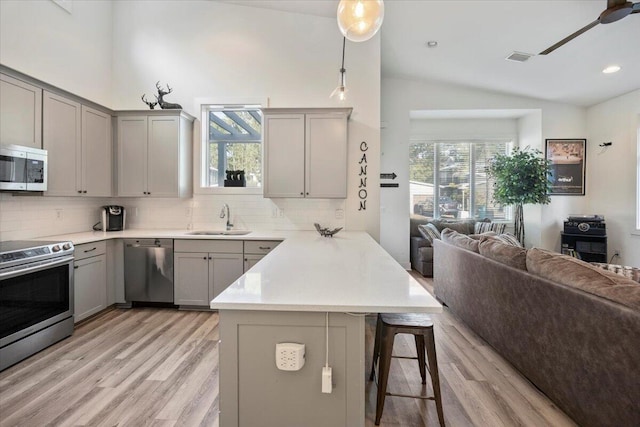 kitchen featuring stainless steel appliances, sink, ceiling fan, hanging light fixtures, and lofted ceiling