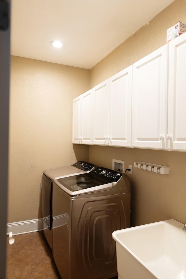 washroom with cabinets, dark tile patterned floors, independent washer and dryer, and sink