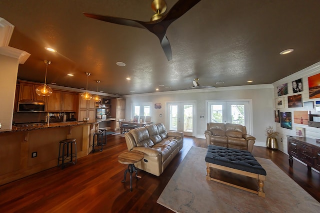 living room featuring ceiling fan, french doors, a textured ceiling, dark wood-type flooring, and crown molding