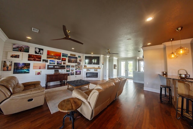 living room featuring ceiling fan, a textured ceiling, dark hardwood / wood-style floors, and crown molding