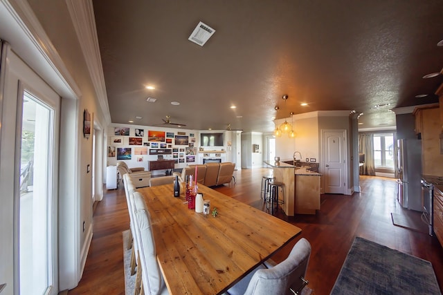 dining area with dark hardwood / wood-style flooring, a textured ceiling, ceiling fan, ornamental molding, and sink