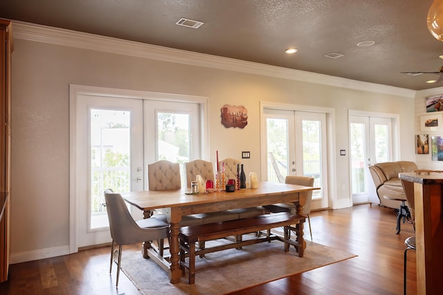 dining room with ornamental molding, wood-type flooring, a textured ceiling, and french doors