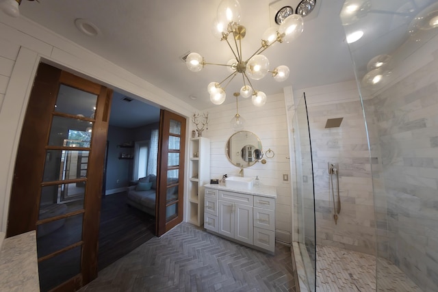 bathroom with an inviting chandelier, parquet flooring, a shower with door, and vanity