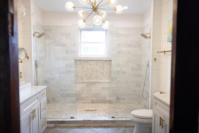 bathroom with a tile shower, vanity, and toilet