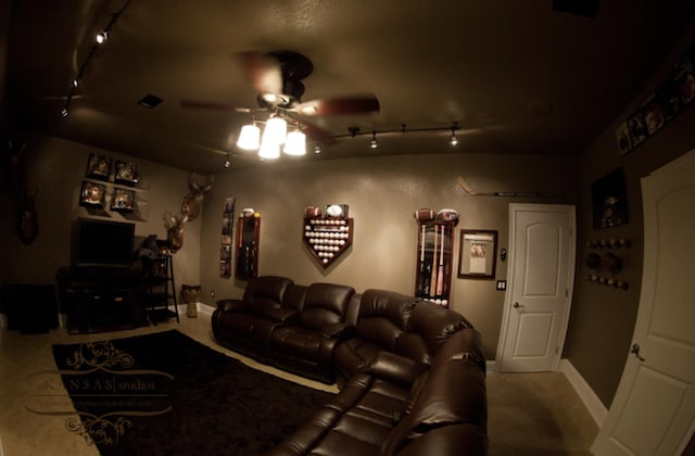 carpeted cinema room with ceiling fan and track lighting