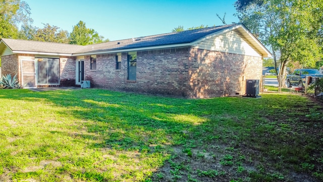 rear view of property featuring a lawn and central air condition unit