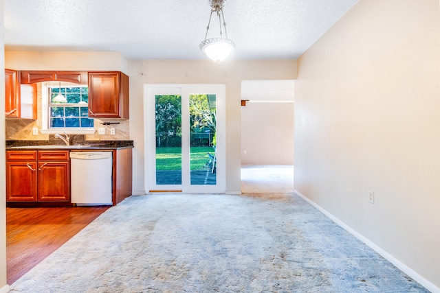 kitchen featuring a healthy amount of sunlight, pendant lighting, white dishwasher, and tasteful backsplash