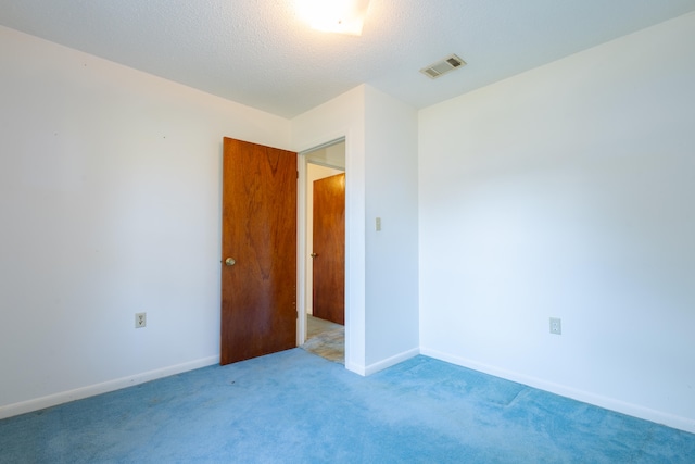 carpeted empty room featuring a textured ceiling