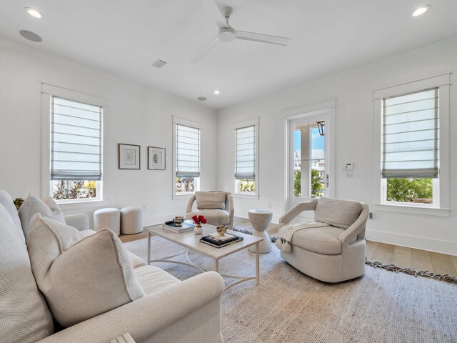 living room featuring a healthy amount of sunlight, ceiling fan, wood-type flooring, and ornamental molding