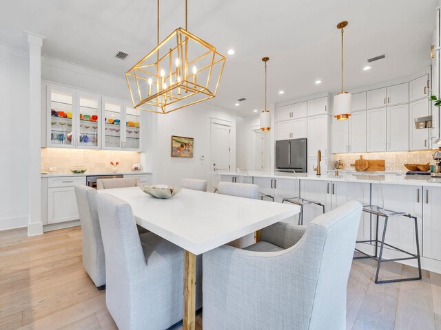 dining space with light hardwood / wood-style floors, an inviting chandelier, and crown molding