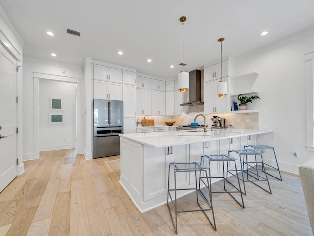 218 White Cottage Rd, Santa Rosa Beach, FL 32459 - kitchen featuring a peninsula, freestanding refrigerator, wall chimney exhaust hood, a kitchen bar, and decorative backsplash