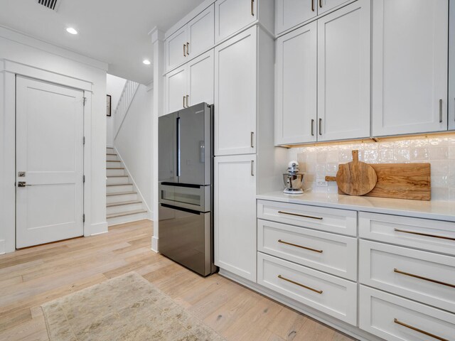 kitchen featuring tasteful backsplash, stainless steel fridge, white cabinets, and light hardwood / wood-style floors