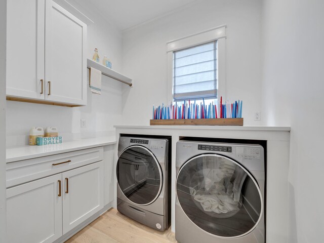 laundry room with cabinets, washing machine and dryer, and light hardwood / wood-style floors