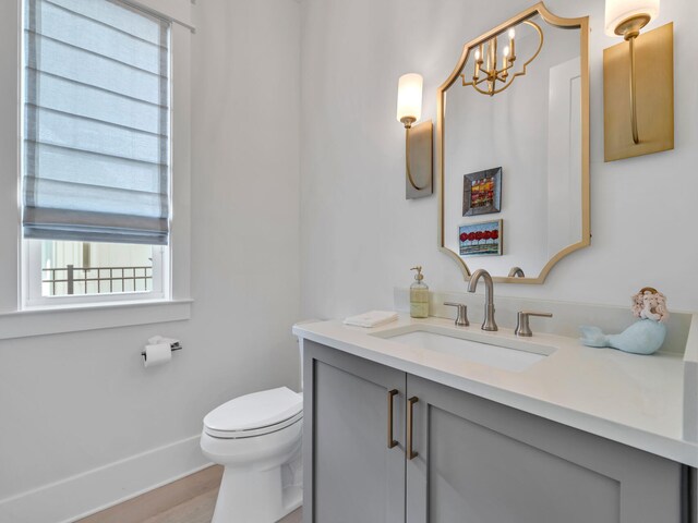 bathroom featuring hardwood / wood-style floors, vanity, toilet, and a chandelier