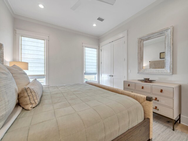 bedroom with a closet, ceiling fan, light hardwood / wood-style flooring, and crown molding