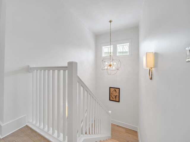 stairs with hardwood / wood-style flooring and a notable chandelier