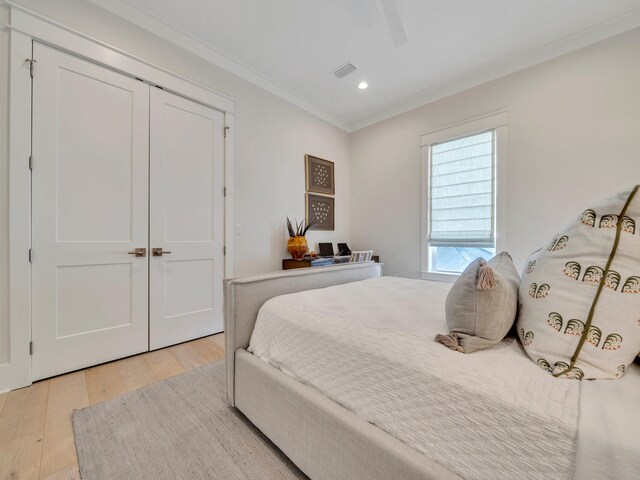 bedroom featuring ceiling fan, a closet, ornamental molding, and light wood-type flooring