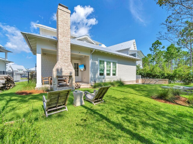 rear view of property featuring a yard and exterior fireplace